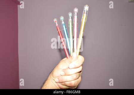 Jeu de plumes multicolores et blanc feutre à bord en main humaine Banque D'Images