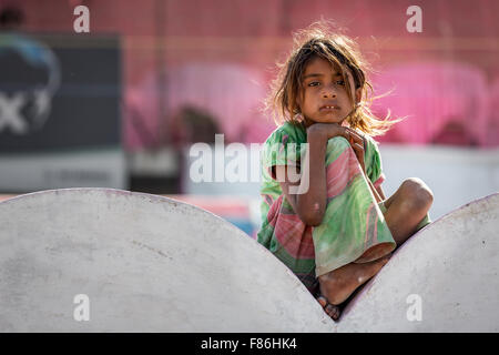 Pauvre fille assis sur un mur, Pushkar, Rajasthan, India Banque D'Images