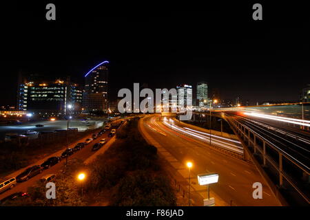 Canary Wharf de Londres, Quartier des bâtiments dans la nuit avec la circulation sur autoroute et le Docklands Light Railway (DLR) Banque D'Images