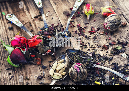 Variétés de thé brassé dans une cuillère de fer sur fond de bois avec des boutons de roses thé Banque D'Images