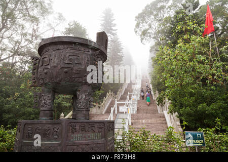 Poignée de gens escalade long vol d'escalier pour le Tian Tan Buddha statue du Grand Bouddha ou à Hong Kong, Chine, à un brouillard mor Banque D'Images