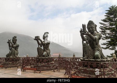 Trois statues bouddhiques en faisant des offrandes à l'Tian Tan Buddha (ou Big Buddha) à Ngong Ping, Lantau Island, Hong Kong, Chine. Banque D'Images