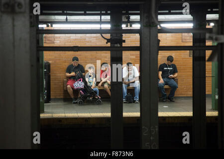 Les gens s'assoient sur le banc de la plate-forme dans la région de métro de New York Banque D'Images