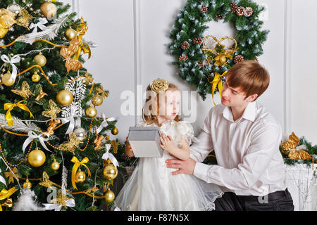 Père et fille se cacher près de l'arbre de Noël des cadeaux. La notion de fête et de plaisir. Le bonheur de la famille. L'enfance. Banque D'Images