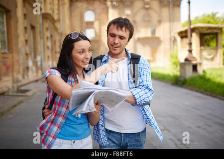 Couple de touristes consulting un guide de la ville à la recherche endroits dans la rue et de pointage Banque D'Images