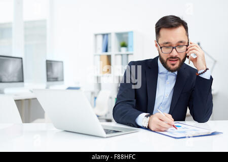 Young Asian businessman speaking on the phone in office Banque D'Images
