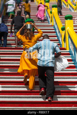 Dévot hindou femme monter les escaliers avec de l'eau pot sur sa tête en fête religieuse annuelle Thaipusam à Batu Caves, en Asie du sud-est, Kuala Lumpur, Malaisie Banque D'Images