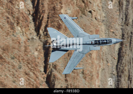 Gros plan d'un Tornado de la Royal Air Force GR4 Jet Fighter tourner brusquement à travers une vallée désertique.