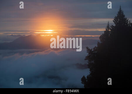 Coucher de soleil dans la brume au-dessus des nuages, vu sur une randonnée en haute montagne dans les Alpes suisses. Banque D'Images