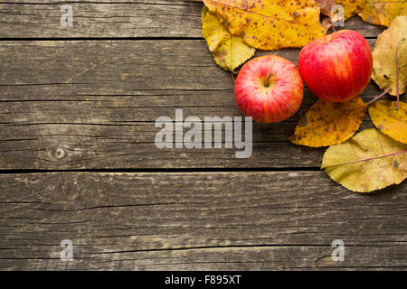 Les pommes d'automne et les feuilles sur la vieille table en bois Banque D'Images
