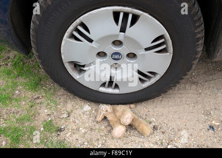 Childs fluffy toy squirrel sous la roue d'une voiture Banque D'Images