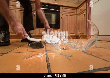 Pile de débris de verre brisé sur le plancher après l'accident et bol en verre pyrex sortit de mains humides renversé posé sur marbre Banque D'Images