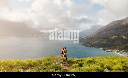 Jeune couple dans l'amour debout sur la colline, avec vue magnifique sur baie et montagnes en arrière-plan. Le couple de l'été romantique va Banque D'Images