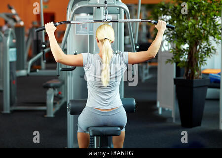 Femme faisant des exercices sur une machine dans une salle de sport lat Banque D'Images