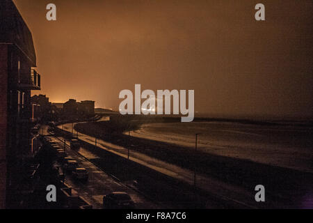 Sandylands Heysham, Promenade, Morecambe Royaume-uni 8 Décembre 2015 Une Eirie vue tenir avec une lumière pour ne pas être vu sur Sandylands Promenade à Morecambe illustré sous la lumière réfléchie sur les nuages de la centrale nucléaire d'Heysham et les lumières sur un ferry au départ du Terminal de Ferry de Heysham. La poursuite de coupures de courant que connaît l'ensemble de Morecambe et Lancaster au lendemain de l'inondation endommagée qui effectue le Lancaster Poste le dimanche. Crédit : David Billinge/Alamy Live News Banque D'Images