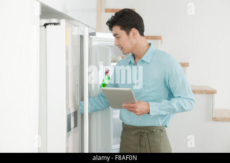 L'homme à l'intérieur du réfrigérateur avec holding a tablet PC Banque D'Images