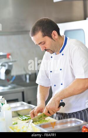 Beau chef habillé en blanc décoration uniforme de la salade de pâtes et de fruits de mer le poisson dans une cuisine moderne Banque D'Images