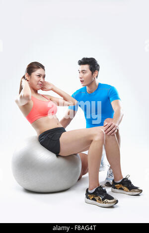 Woman doing sit-ups sur ballon de gymnastique et l'entraînement de l'homme à côté d'elle Banque D'Images