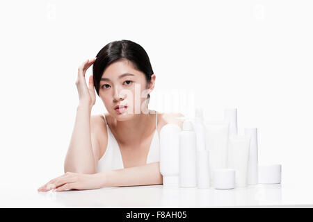 Femme assise à la table avec sa main près de sa tête avec différents produits sur la table Banque D'Images