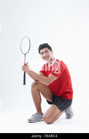 Homme assis mains pliage avec une raquette de badminton fixant à l'avant Banque D'Images