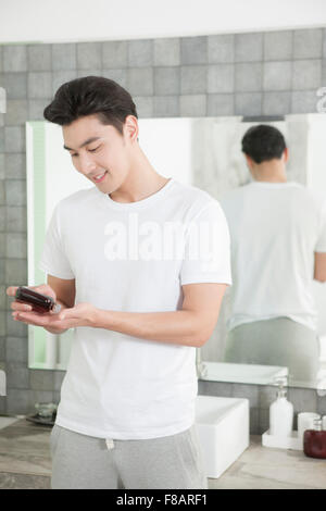 Portrait of young smiling man à l'aide de bains cosmétiques en regardant vers le bas Banque D'Images