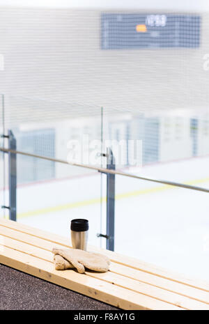 Tasse thermos et mitaines sur banc de la patinoire à l'arena Banque D'Images