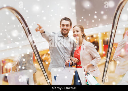 Couple with shopping bags sur escalator in mall Banque D'Images