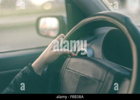 La pilote mains ronchonnant volant, femme au volant d'une voiture, avec l'image aux couleurs rétro selective focus Banque D'Images