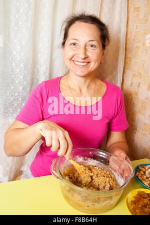 Femme mature en pâte dans le plat. L'une des étapes de la cuisson du gâteau au miel. Voir la série Banque D'Images