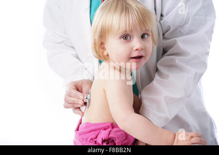 Le médecin examine tout-petit enfant et à l'écoute de cœur et les poumons avec stéthoscope. La fille de bébé est heureux, isolated on white Banque D'Images