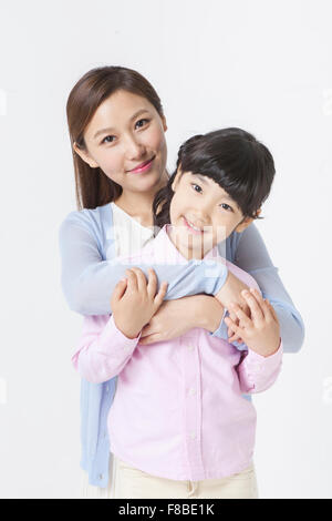 Mother hugging her daughter de derrière les deux yeux de l'avant avec un sourire Banque D'Images
