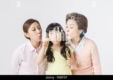 Young Girl holding des bulles de savon et il souffle avec de jeunes femmes adultes et senior woman Banque D'Images