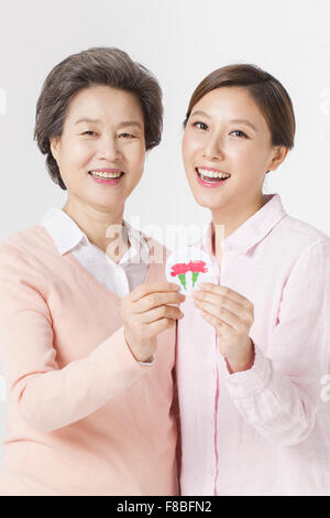 Mère et fille tenant un emblème de fleurs d'oeillet et de l'avant avec un sourire Banque D'Images