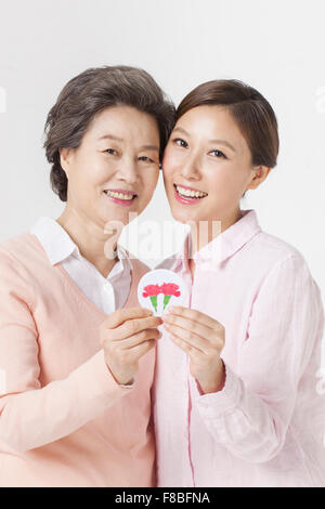 Mère et fille tenant un emblème de fleurs d'oeillet et de l'avant avec un sourire Banque D'Images