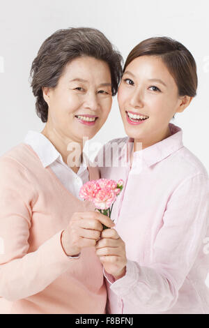 Mère et fille tenant un emblème de fleurs d'oeillet et de l'avant avec un sourire Banque D'Images