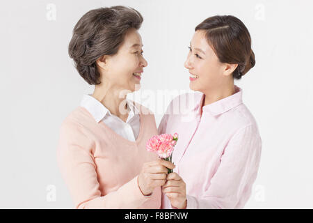 Mère et fille fleurs carnation tenant ensemble et regarder Banque D'Images