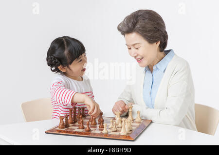 Jeune fille et sa grand-mère assis à table jouant aux échecs ensemble Banque D'Images