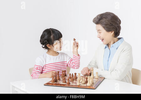 Jeune fille et sa grand-mère assis à table jouant aux échecs ensemble Banque D'Images