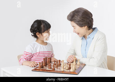 Jeune fille et sa grand-mère assis à table jouant aux échecs ensemble Banque D'Images