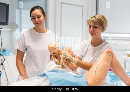 La prestation d'un étudiant sage-femme mannequin bébé à partir d'un mannequin adulte, les deux mannequins sont équipés de capteurs, de son et d'autres dispositifs conçus pour simuler un grand nombre des conditions de l'accouchement, Limoges, France. Banque D'Images