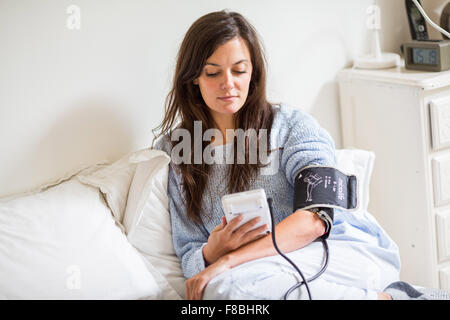 Femme de prendre sa pression artérielle avec un tensiomètre. Banque D'Images