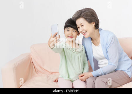 Grand-mère et petite-fille, assise sur un canapé et de prendre une photo de soi Banque D'Images