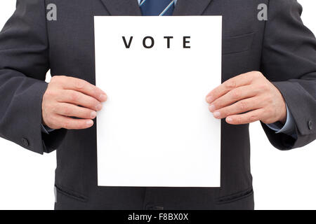 Man in suit, tenant une feuille blanche avec titre vote en face de lui. L'image a été fait en studio et isolé sur blanc retour Banque D'Images