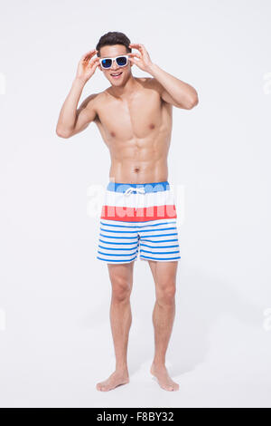 Pantalon homme musclé en natation et lunettes debout et tenant ses lunettes Banque D'Images
