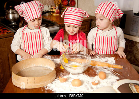 Trois petits chefs bénéficiant dans la cuisine faire grand désordre. Litt Banque D'Images