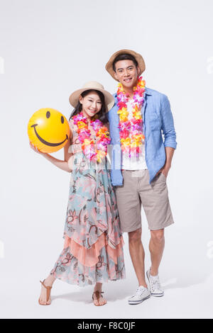 Dans l'homme tenues décontractées et un chapeau avec une femme en robe longue tenant un ballon de plage à la fois dans un chapeau et de l'avant avec Banque D'Images