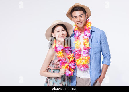 Couple en tenues décontractées portant un chapeau et collier de fleurs les deux yeux de l'avant avec un sourire Banque D'Images