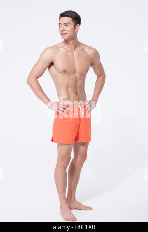 L'homme musclé en natation short debout avec ses mains sur sa taille et à côté Banque D'Images