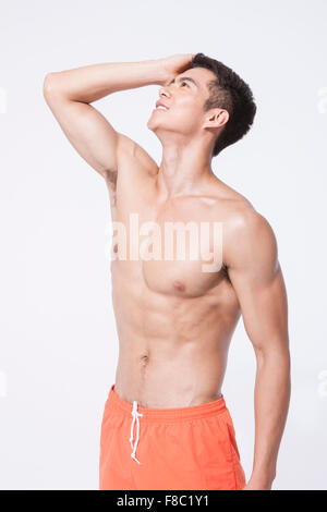 L'homme musclé en natation short mettant sa main sur sa tête et en mettant sa tête Banque D'Images