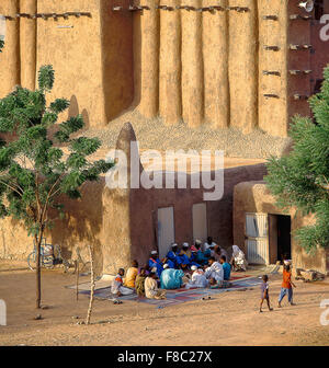 Hommes locaux assis devant la Grande Mosquée de Djenné, Mali. Banque D'Images